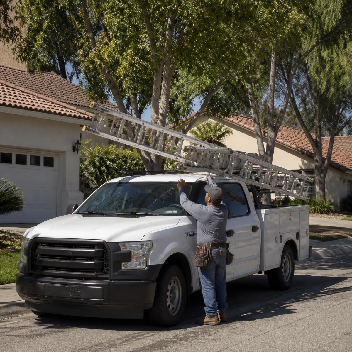 Local roofing crew unloading a ladder on a Fresno residential street